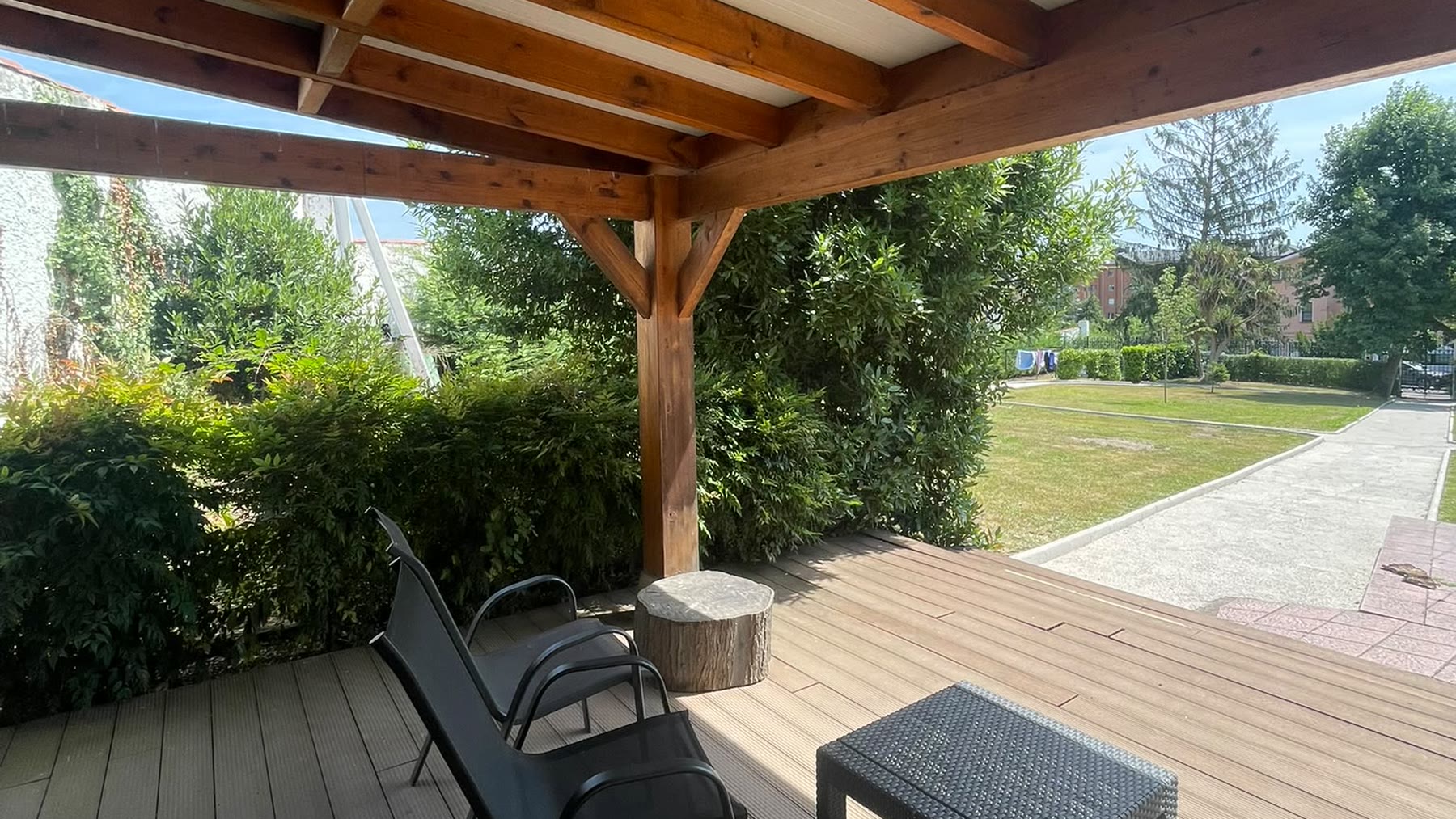 Porche de madera del jardín de la clínica, con butacas y vistas a la pradera