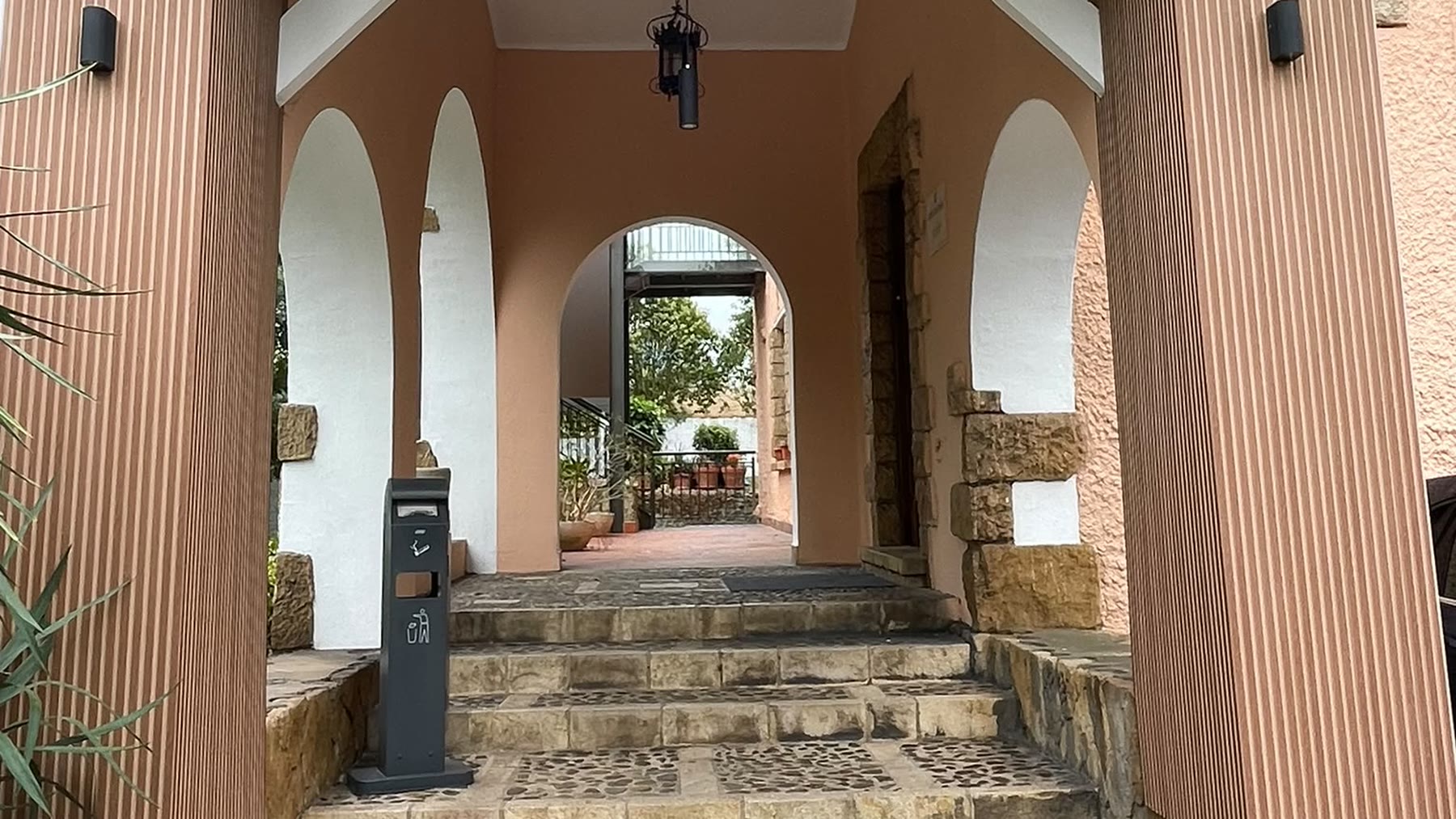 Pórtico de entrada a la clínica, con arcos encalados y suelo de canto rodado
