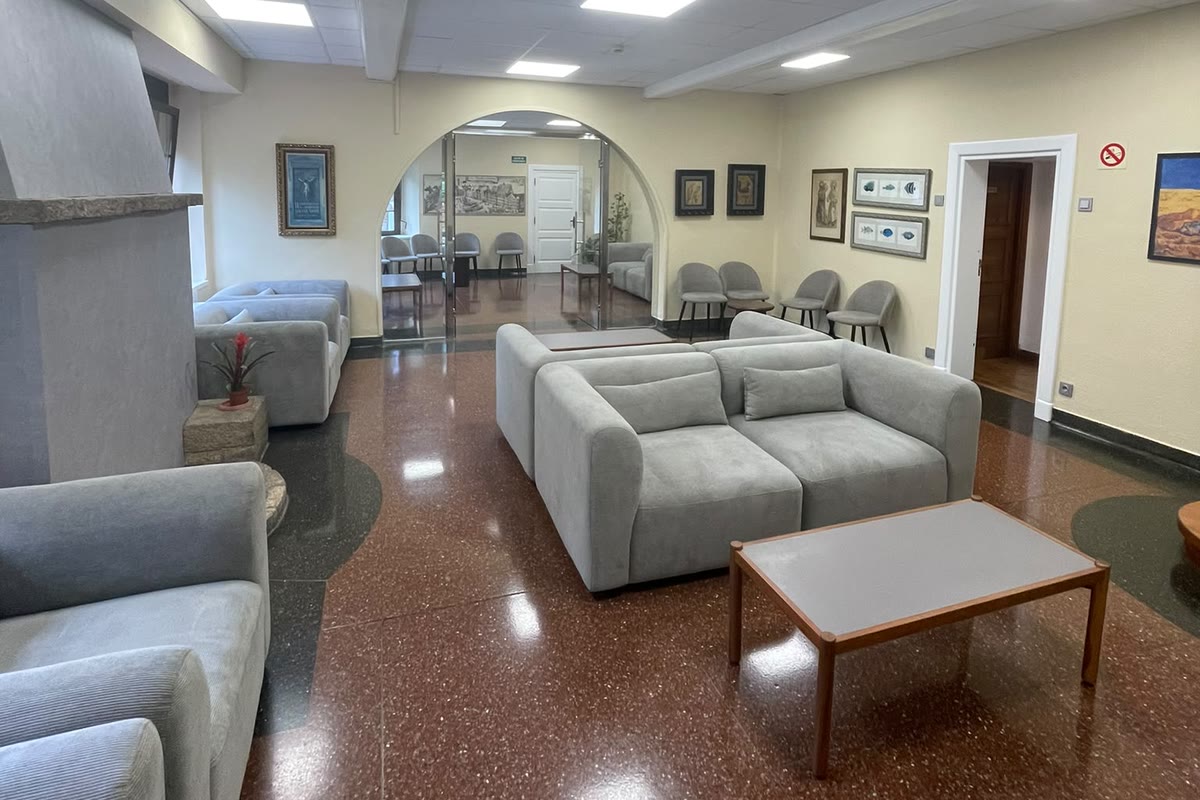 Sala de estar amplia con sofás grises, chimenea y suelo de terrazo